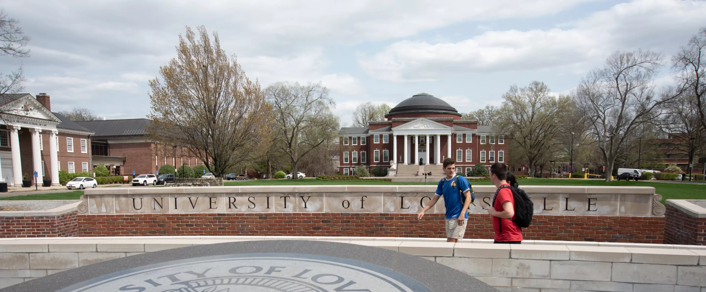 Three students walking past the 3rd Street entrance with Grawemeyer Hall and the School of Law in the background.