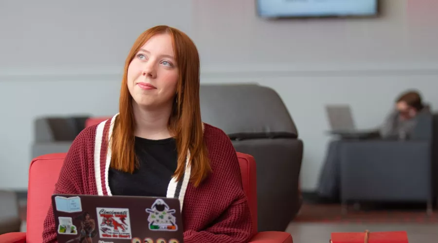 A student pauses in thought while working on a laptop in the Belknap Academic Building