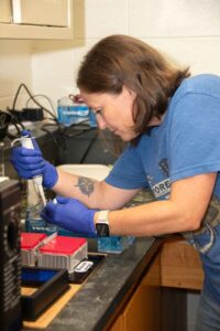 A woman loads fluids into a test tube in a lab.