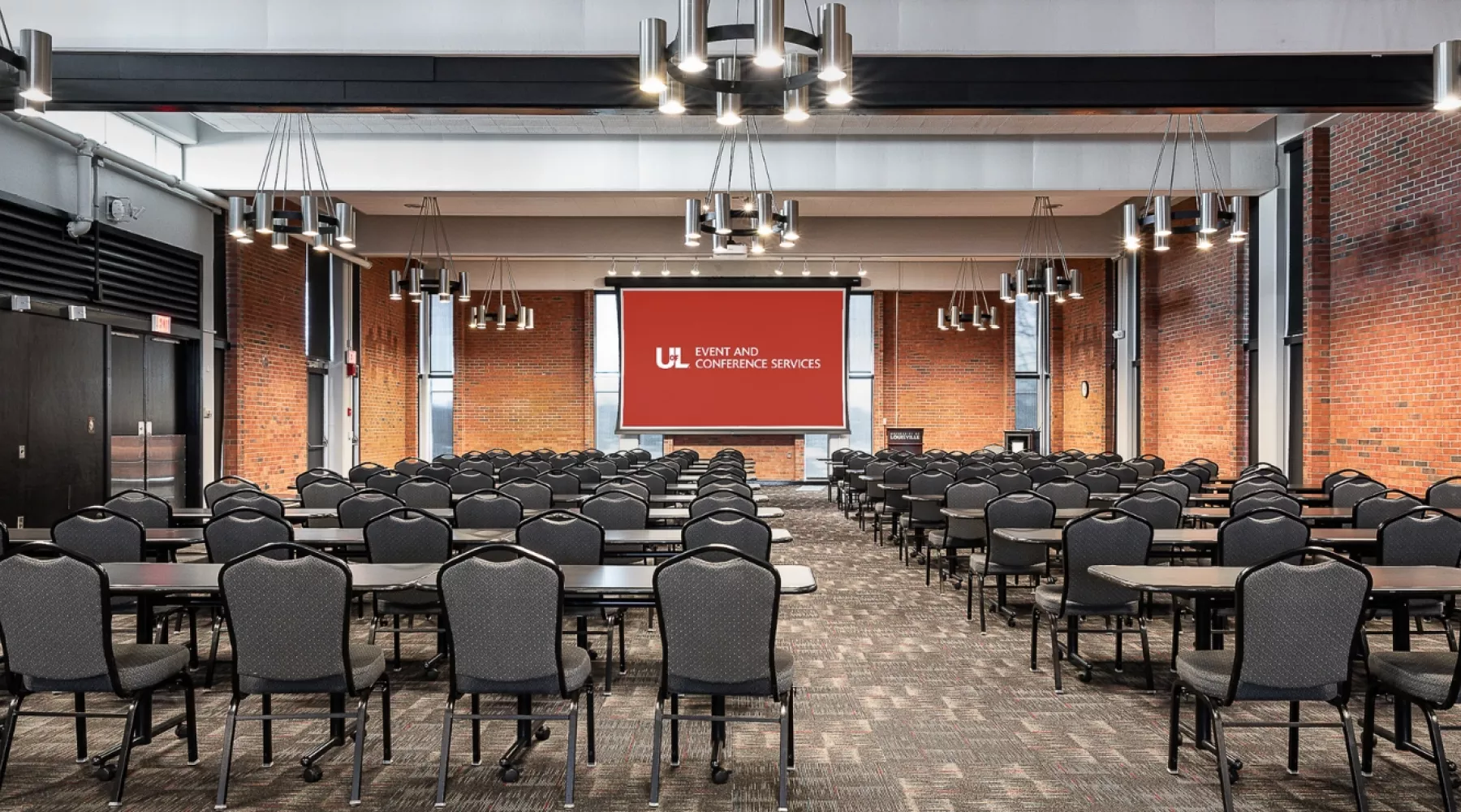 Balltoom with projector screen and multiple rows of tables and chairs