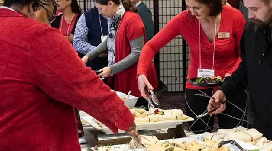 People using tongs to pick up food from catering dishes