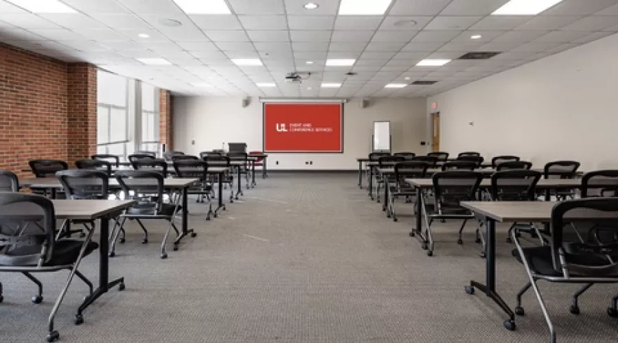 Classroom with projector screen and rows of tables and chairs