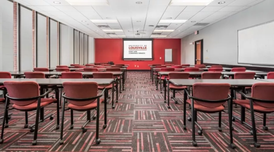 Classroom with projector screen and multiple rows of tables and chairs