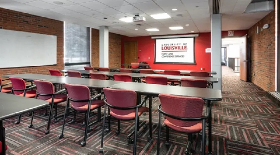 Classroom with projector screen and multiple rows of tables and chairs