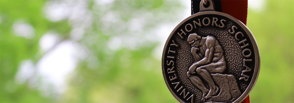 The Honors Scholar graduation medal against an outdoor background. 