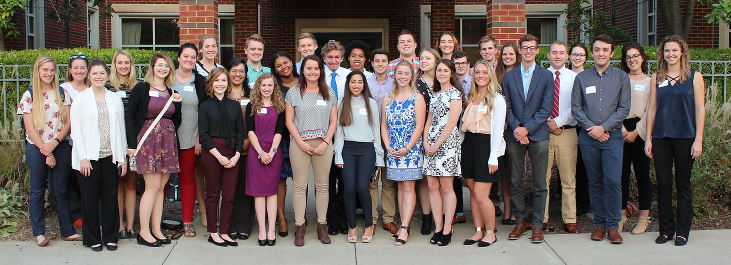 A group of students stands outside dressed in business-casual clothing.