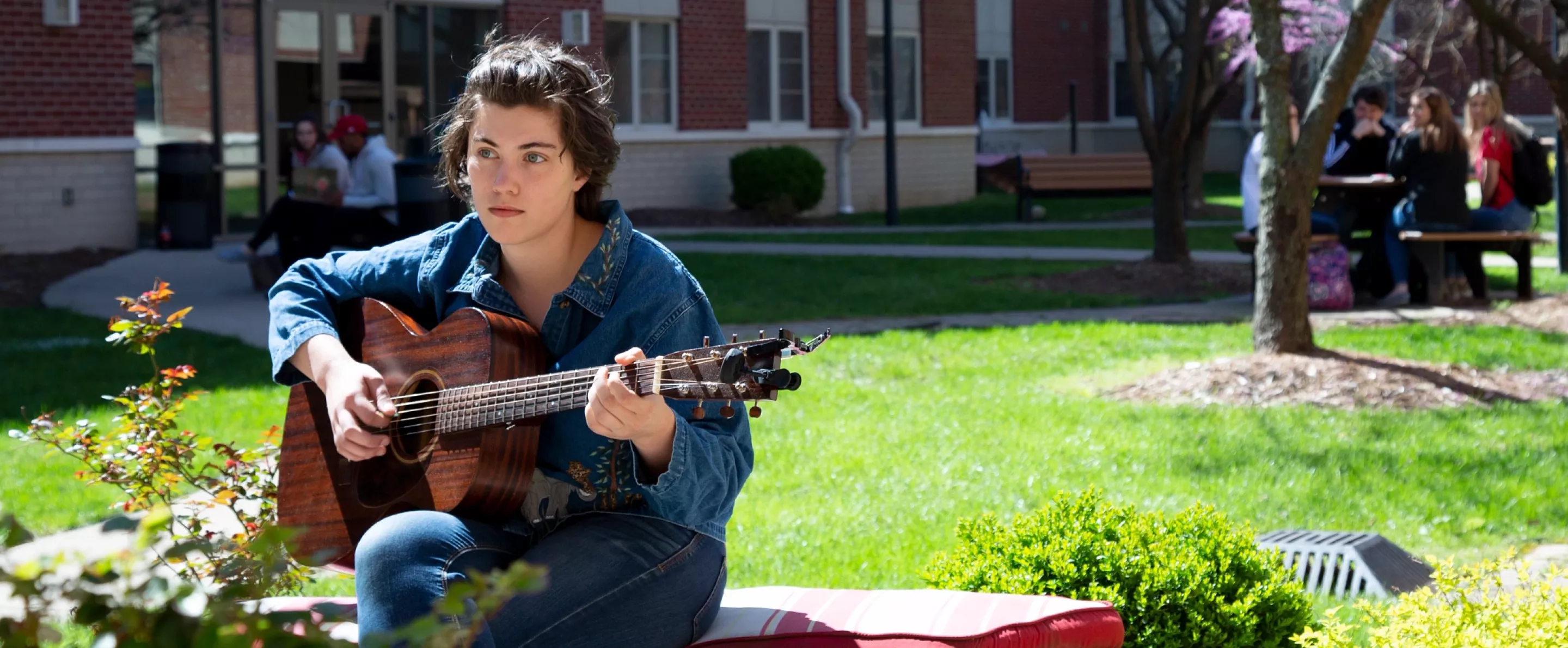 Student plays guitar on a spring day