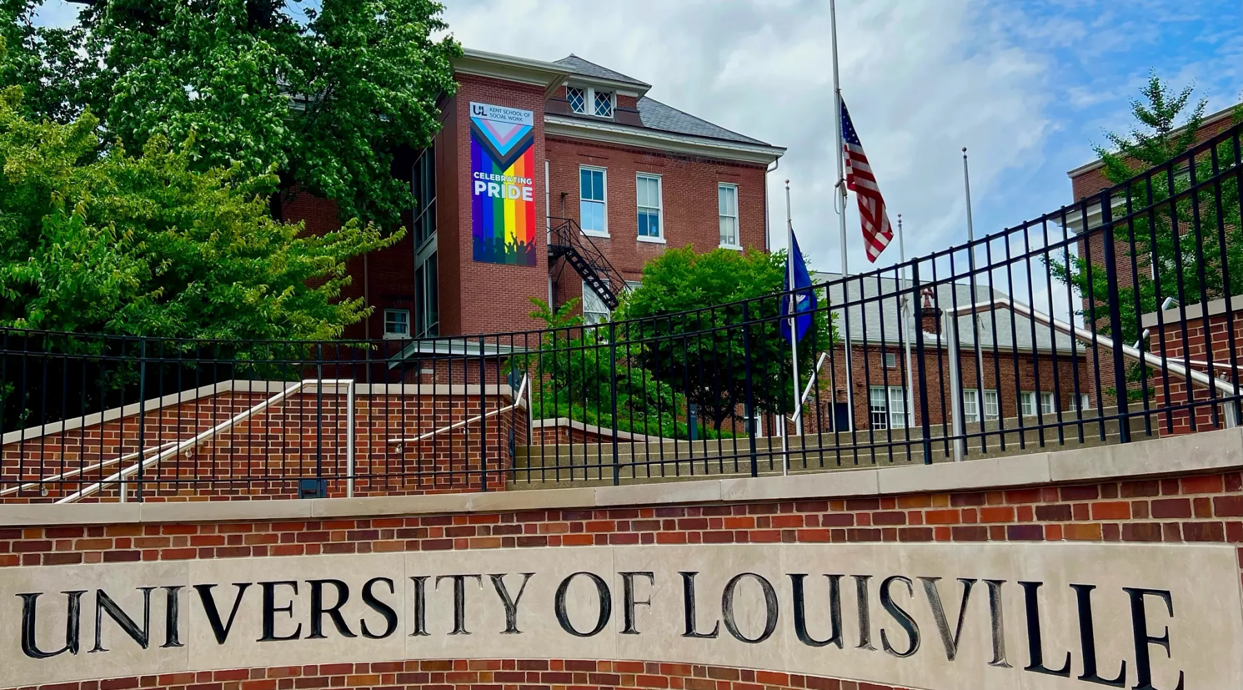 Eye level view of outdoor stairway on the corner of Cardinal boulevard. "University of Louisville" is carved out in brick and in the background a