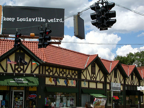 picture of a corner store with a large billboard over it reading, keep Louisville weird.