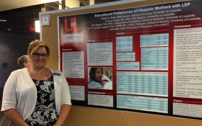 student standing in front of a research poster