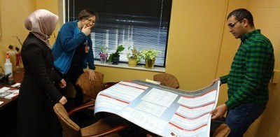 Office of Nursing Research faculty and students review a poster in an office.