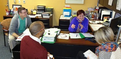Research students and staff gathered around a desk in the research office.