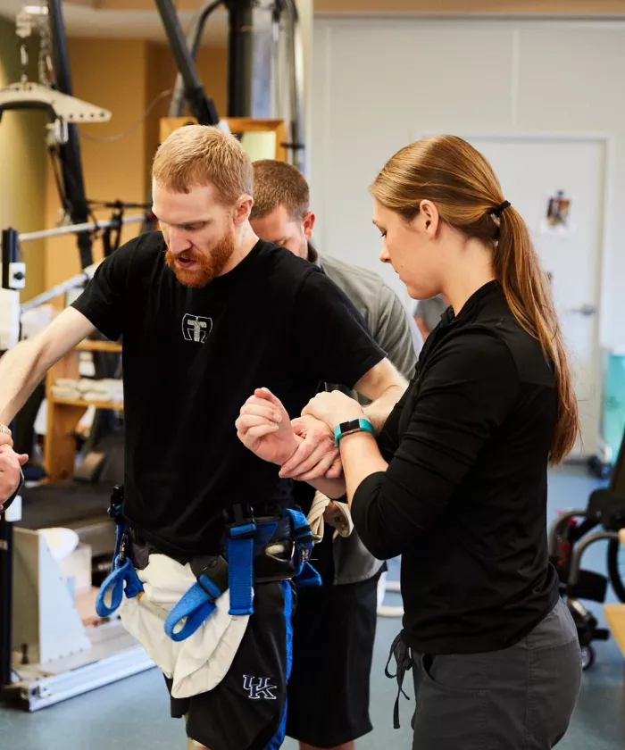 Researchers working with a patient in the therapy gym.